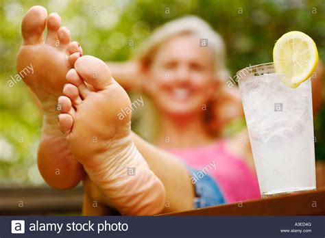 Close-up of a mature woman's foot with a glass of lemon ...